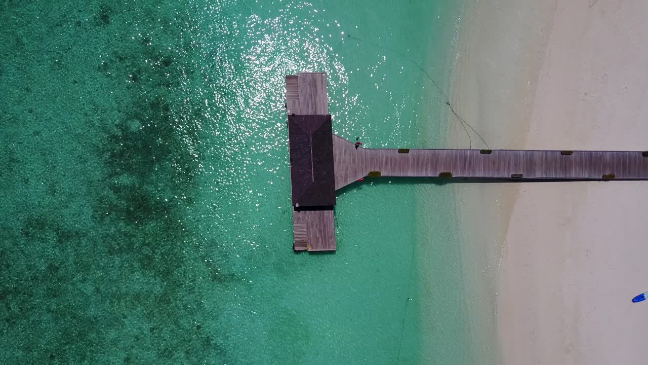 Veduta aerea di un molo vuoto in acque tropicali limpide.