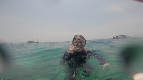 pov footage from a gopro captures a woman floating on the surface of the sea, wearing a diving mask