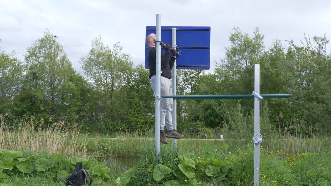 수평 막대에서 야외에서 풀업 운동을 하는 강한 근육질의 남자 - 와이드 샷