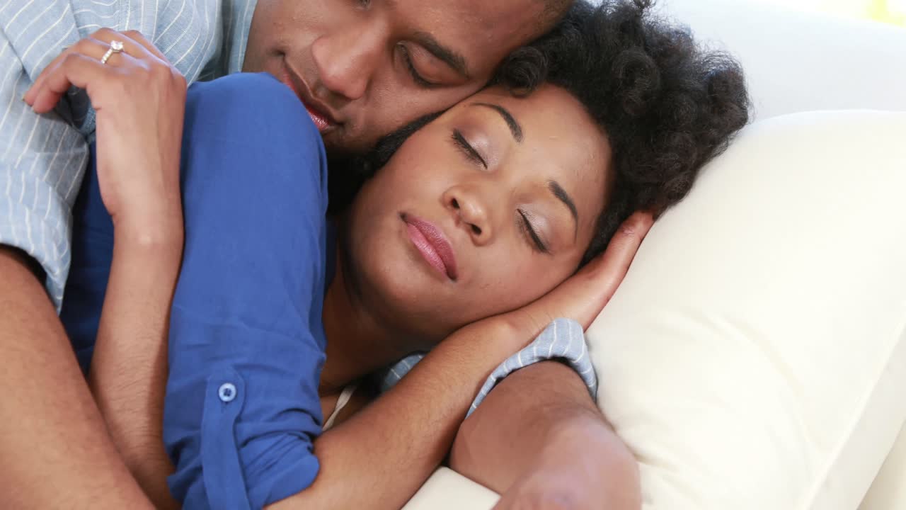 Attractive couple lying on the couch cuddling