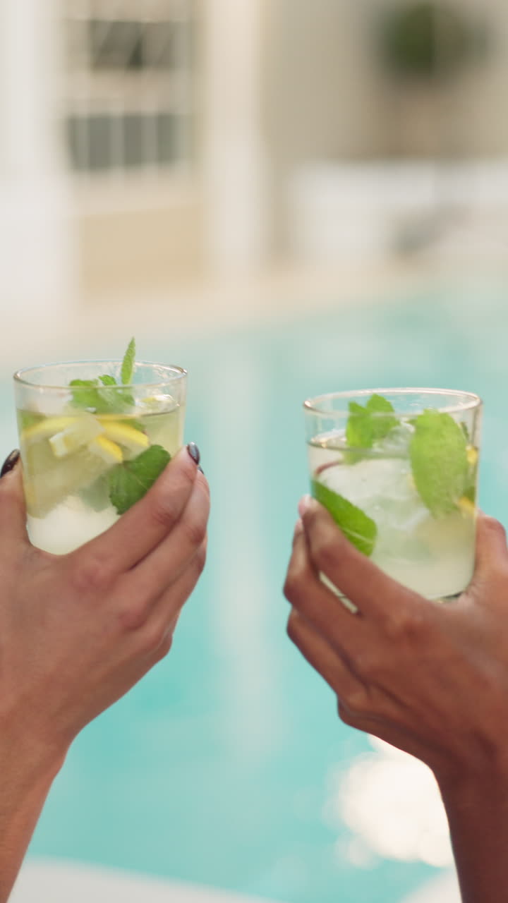 Close Up of Hands Toasting with Refreshing Cocktails by a Pool
