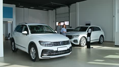 sala de exposición de automóviles con vendedor y cliente