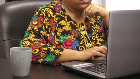 Business-Casual-dressed-African-American-woman-sitting-in-office-at-desk-checking-emails-on-computer
