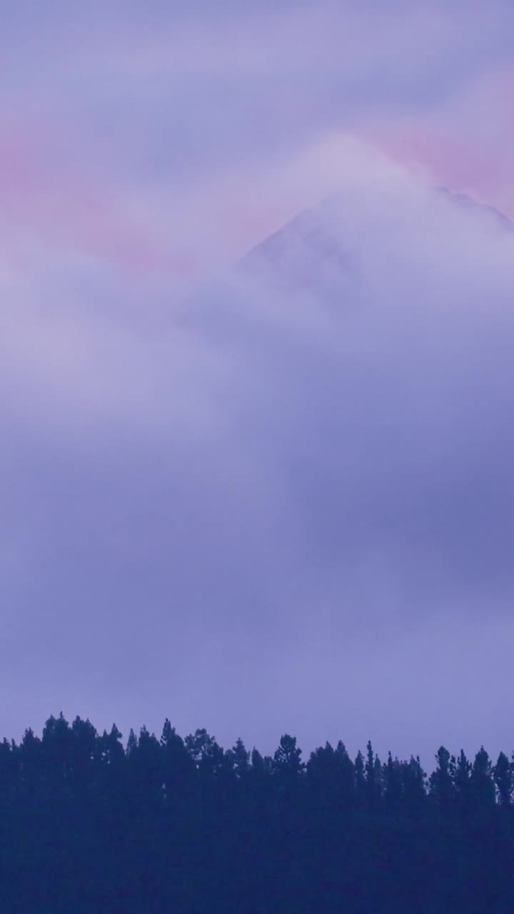 Nuvole Viola che Fluttuano sopra una Montagna Innevata e una Foresta