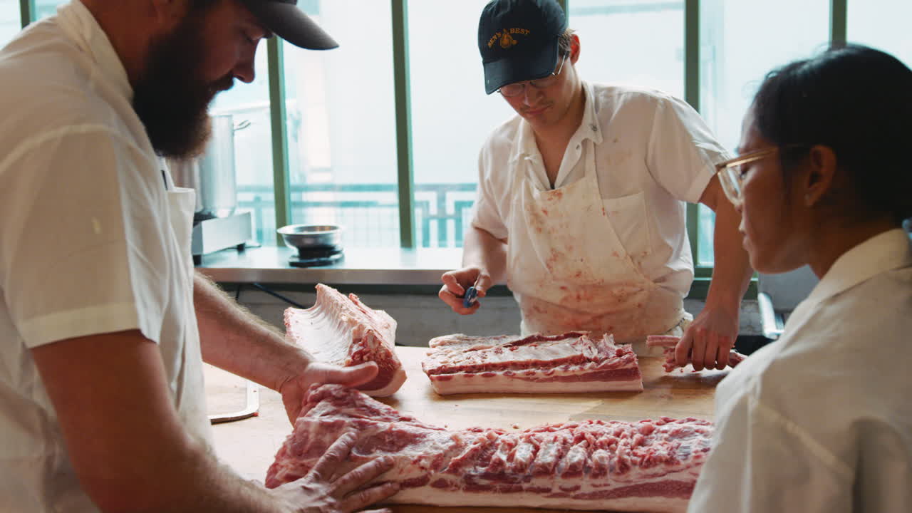 Butcher training colleague to prepare meat at butcher's shop