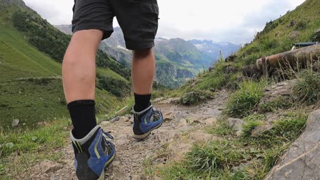 un hombre en pantalones cortos cruza un río y salpica agua del arroyo, camina en los alpes suizos, obwalden, engelberg