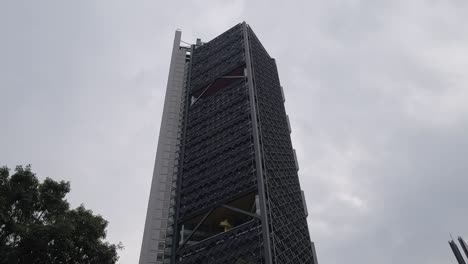 slow motion establishing shot of a unique skyscraper designed with glass