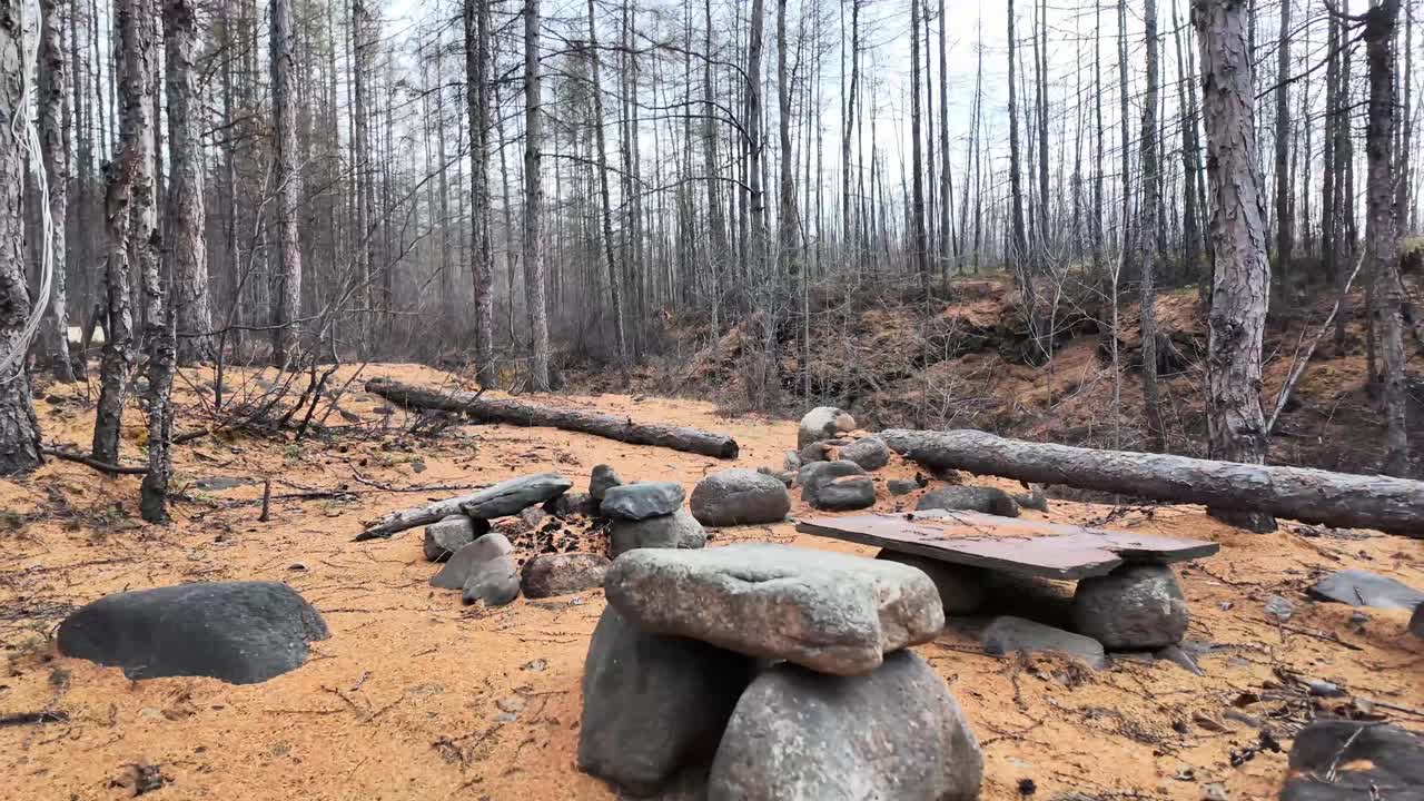 Stone fire pit and old camp in the autumn forest