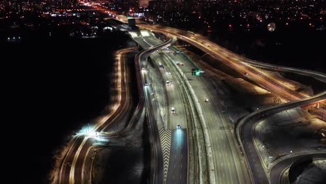 aerial flyover traffic jam interchange road at night, drone shot top down view roadway intersection in modern city in evening