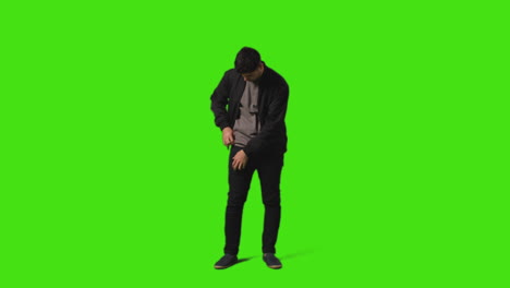 Young-Man-Answering-Call-On-Mobile-Phone-Standing-Against-Green-Screen-Studio-Background