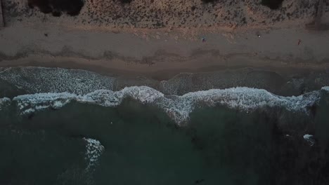 Vista-De-Arriba-Hacia-Abajo-De-Una-Playa-Tranquila-Con-Olas-Espumosas-Que-Se-Lavan-En-La-Costa-En-Menorca,-España---Tiro-Estático-Aéreo