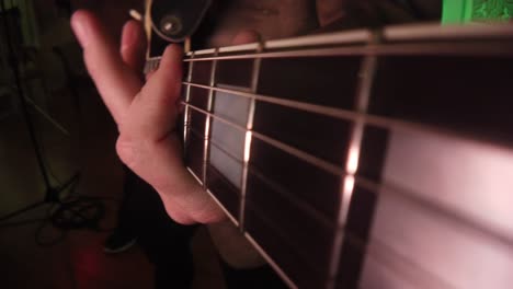 hands are seen strumming guitar strings. cool angle