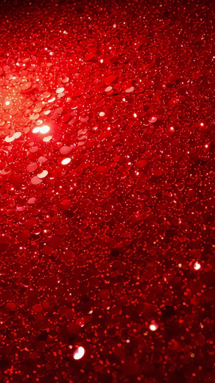 Vertical video: Moving angled light sweeping red glitter in studio, camera tilting, creating glints