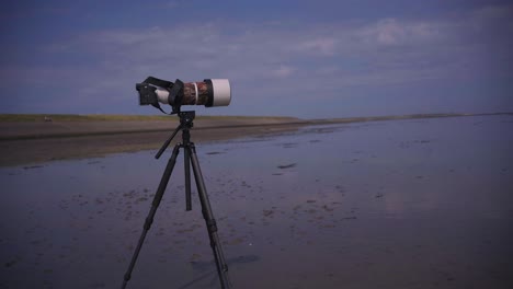 gran teleobjetivo en la cámara y trípode estable en la playa en texel wadden