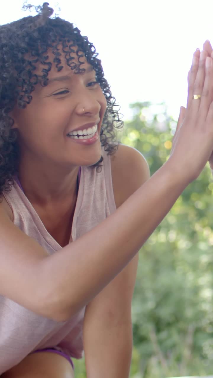 Video verticale: Donna riccia sorridente con top rosa che alza la mano per salutare un'amica di ritorno, boccale.