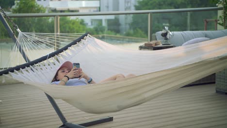 wide shot of teenage girl texting on hammock