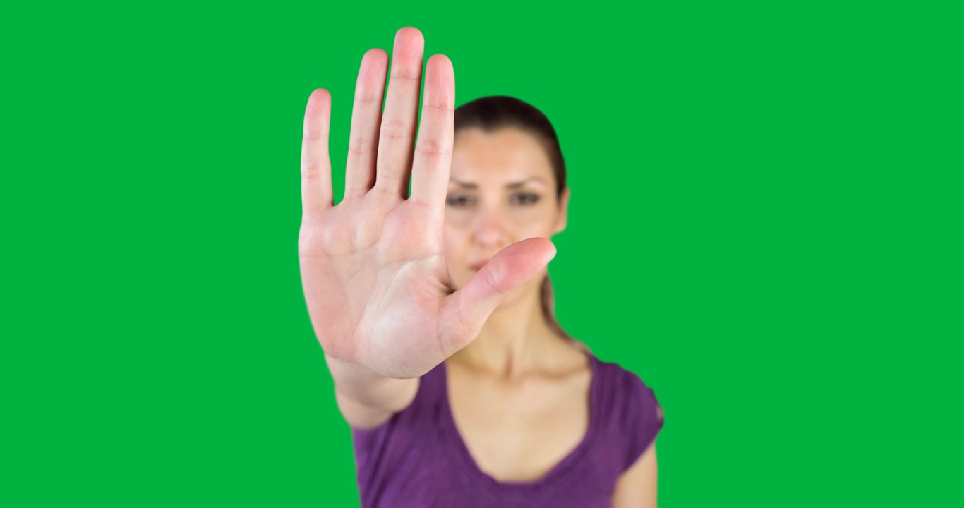 Ritratto di donna caucasica che fa il segno di stop con la mano su sfondo nero