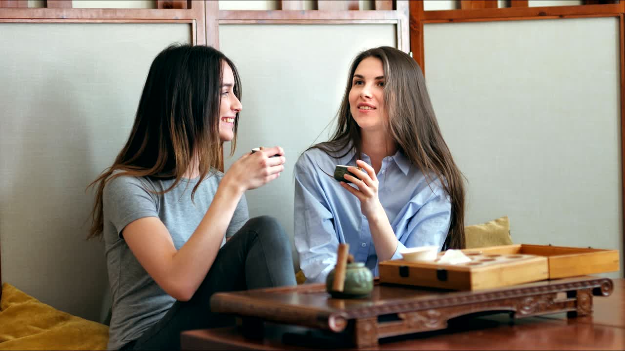 dos chicas bonitas hablan y beben té en un café.