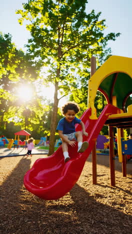 a young boy playing on a slide at a sunny outdoor playground