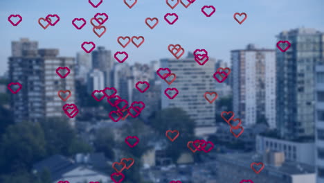animation of multiple red heart icons floating against aerial view of tall buildings