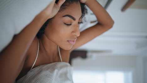 relaxed lady stretching at morning bed closeup. african serene girl waking up
