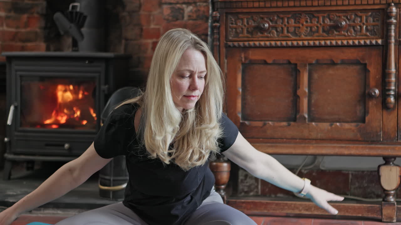 Woman doing yoga near a fireplace