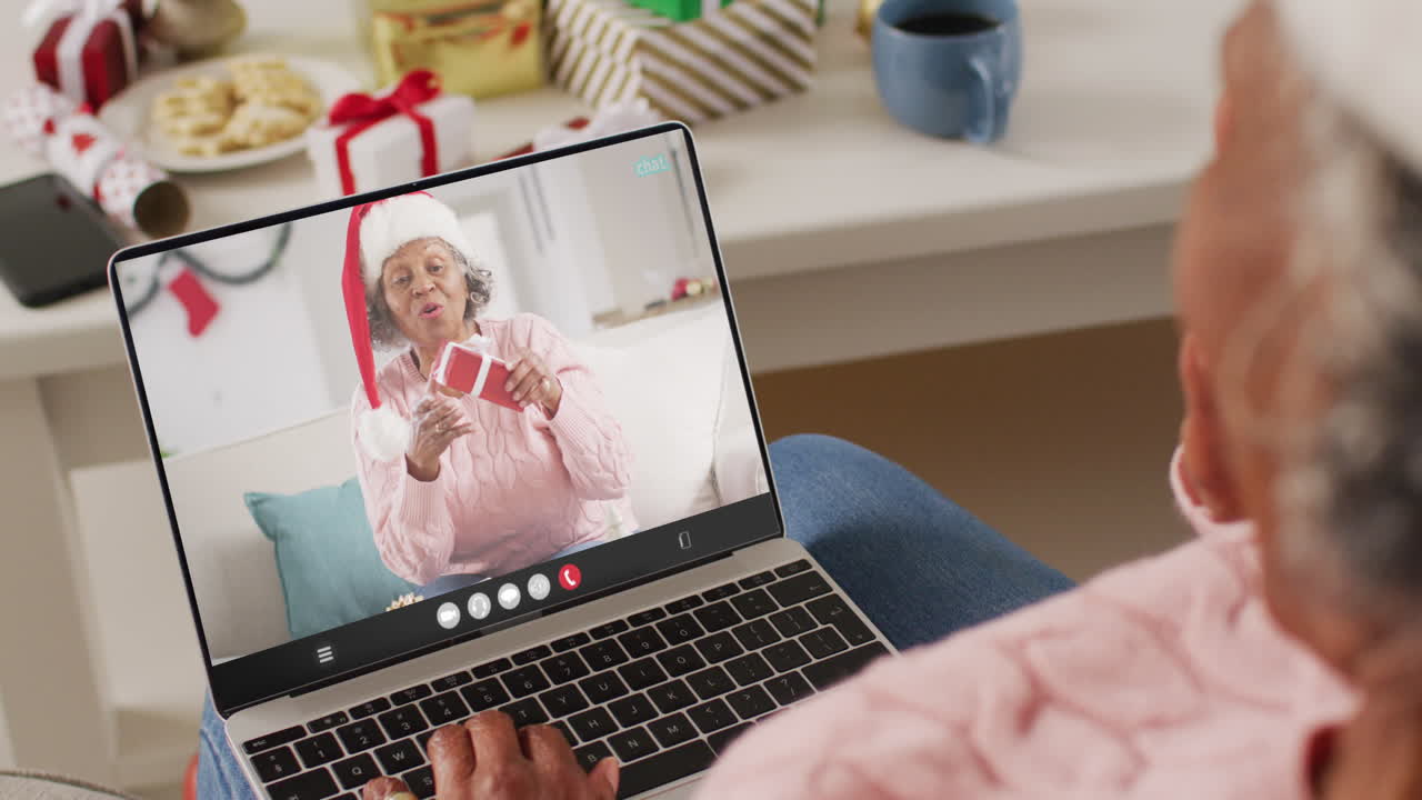 Donna afroamericana con cappello di Babbo Natale in videochiamata su laptop con una donna afroamericana
