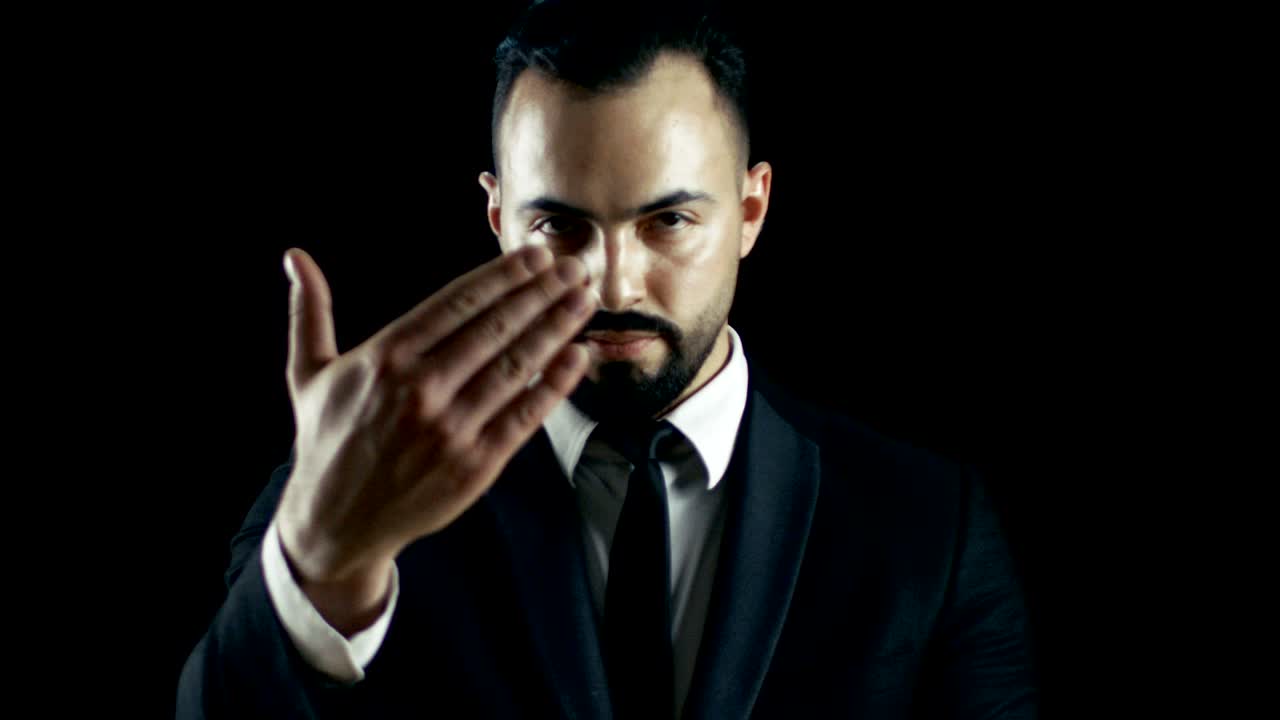 어두운 슈트를 입은 재능있는 젊은 마술사가 실제 불공을 던지고 는 트릭을 수행합니다.