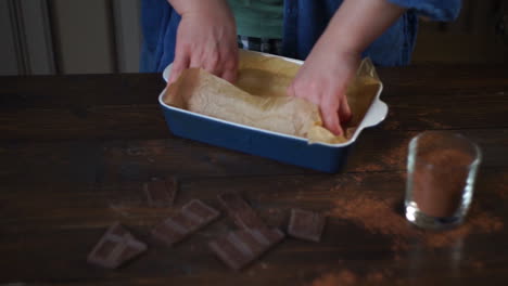 hands put cooking paper in ceramic form. baking utensils