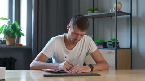 hombre escribiendo en un cuaderno en un escritorio