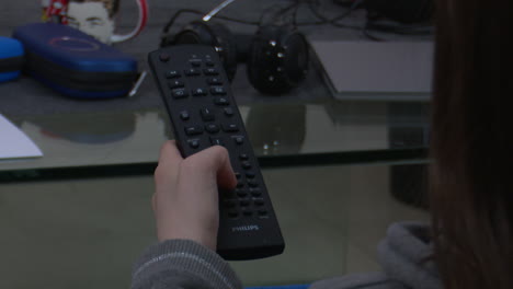 persona que sostiene un control remoto de la televisión