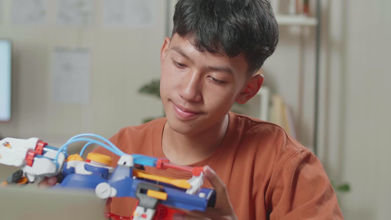 primer plano de un niño asiático comprobando y comparando una mano cyborg con la imagen en una computadora portátil en casa mientras está en casa
