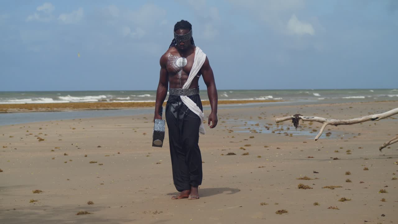 Su una spiaggia tropicale, un uomo muscoloso e dalla pelle scura è perfettamente trasformato in Nekharis tramite cosplay.