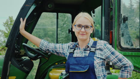 conductora de tractor de mujer confiada parada cerca de su tractor