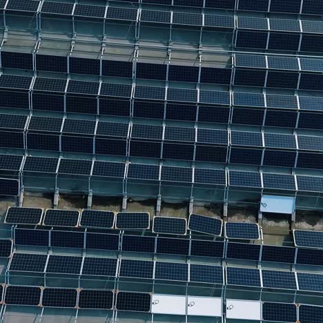 blue solar panels on roof of building. construction of innovative photovoltaic solar cells. alternative source of energy. camera moving down. aerial view