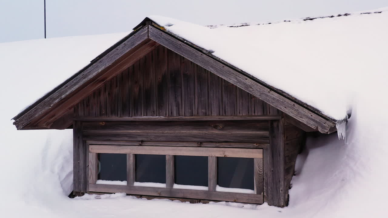 겨울에는 눈 덮인 집 지붕과 고드름이 있는 나무 다락방