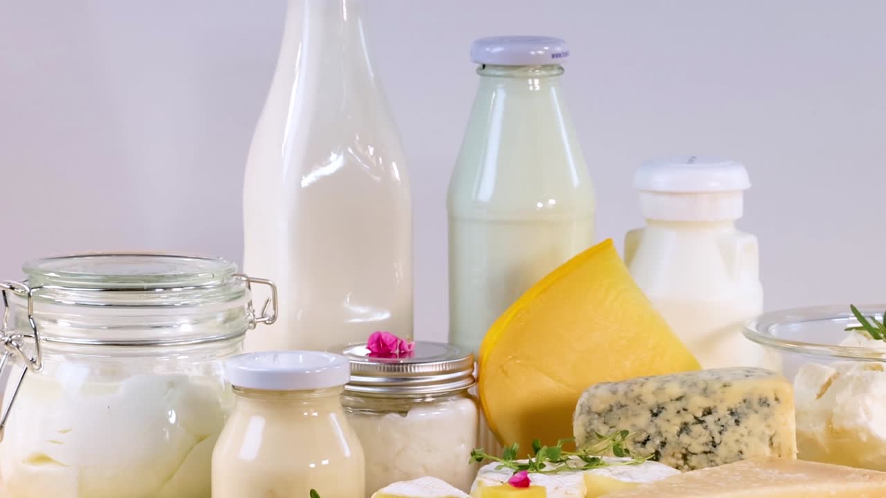 A variety of dairy items including milk, cheese, and yogurt displayed on a wooden surface.