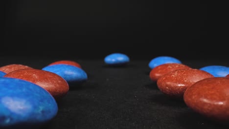 close up shot of blue and red sugar-coated chocolate confectionery on dark background