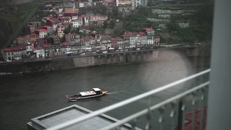 Traditional-boat-sailing-on-Douro-River-with-a-view-of-Porto's-historic-riverside-buildings