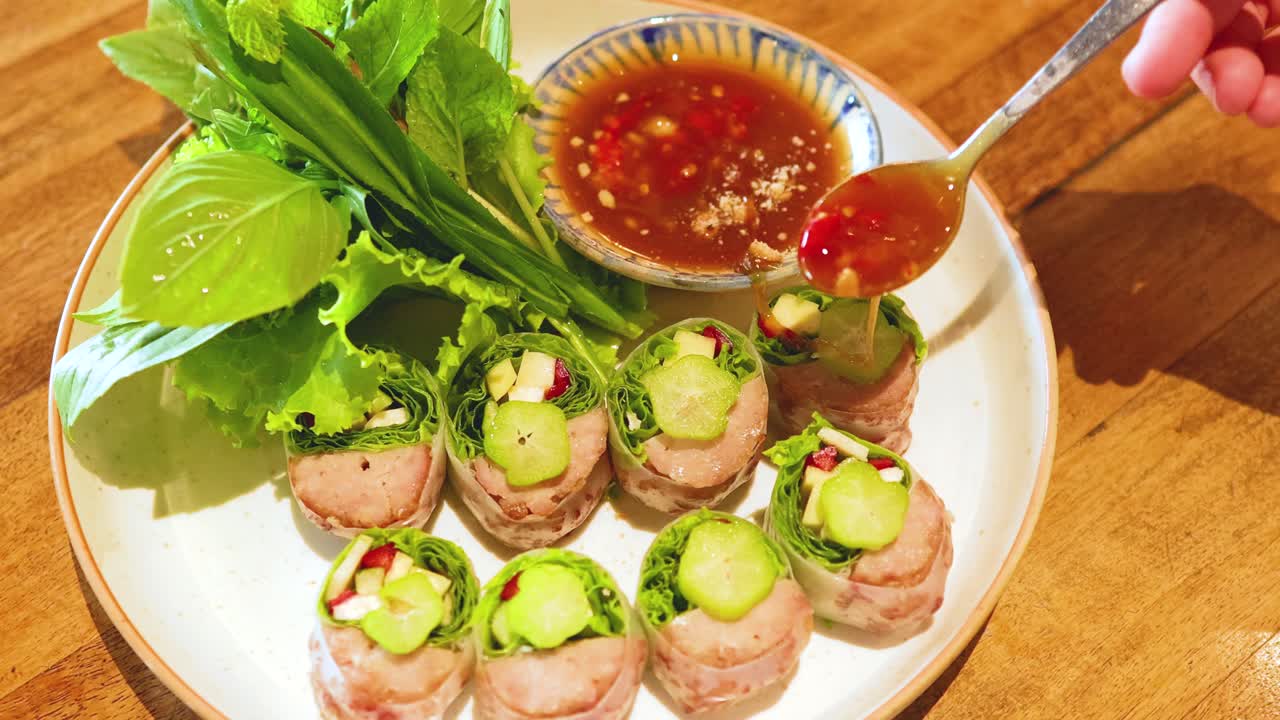 A sequence of frames showing Vietnamese pork rolls being garnished with sauce, highlighting vibrant colors and fresh ingredients