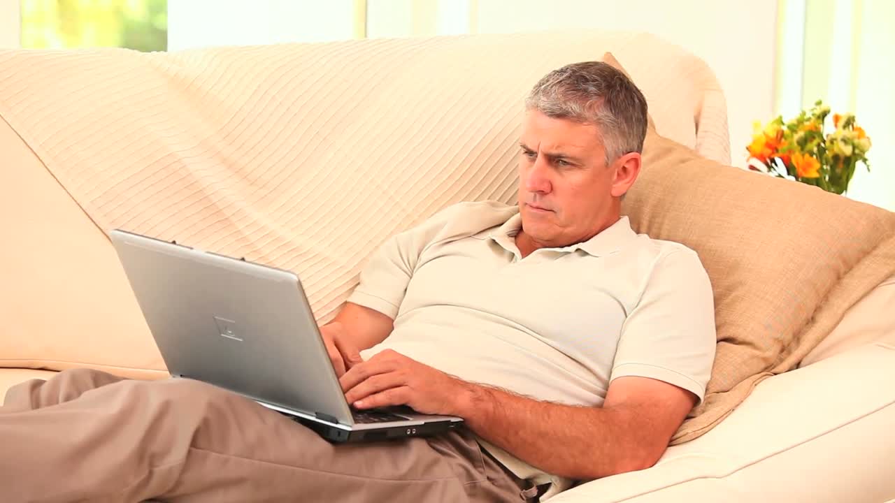 hombre acostado en el sofá usando una computadora portátil