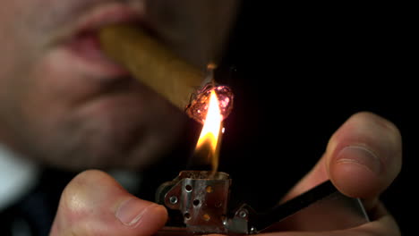 businessman lighting his cigar on black background