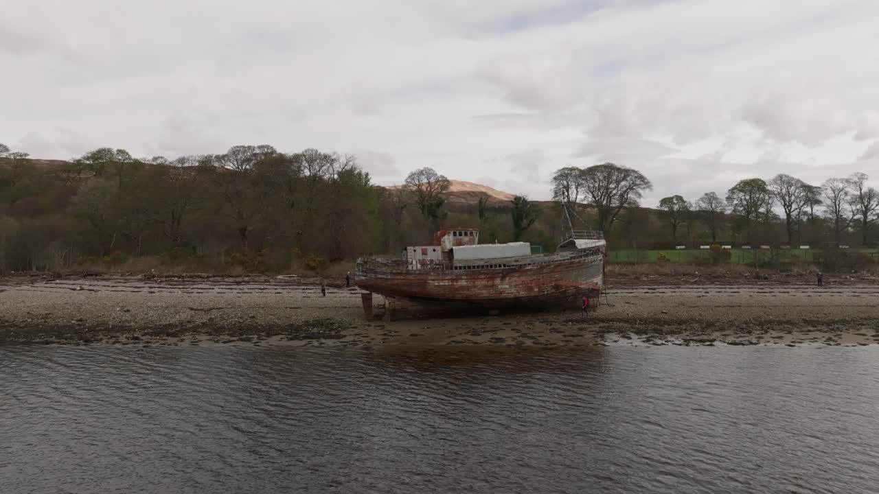 Static shot of a group of tourists exploring the Corpach Shipwreck landmark