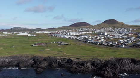 beautiful green grass golf club course on volcanic island with small town, aerial