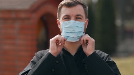 portrait of a young priest wearing a medical mask