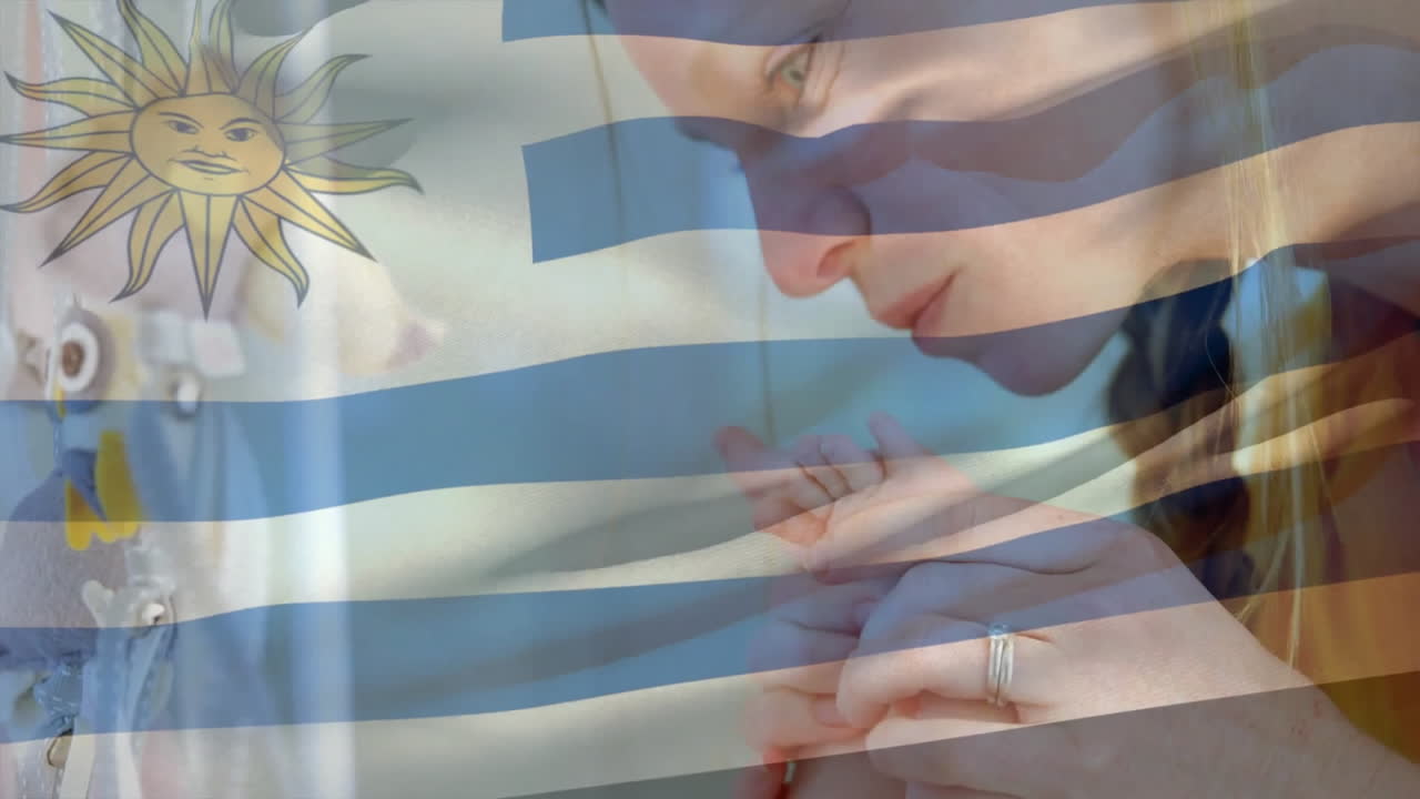 animación de la bandera uruguaya sobre la madre caucásica besando los pies del bebé