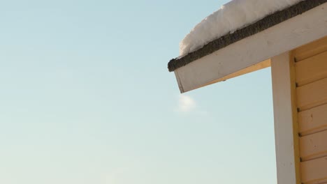 Water-drops-falling-from-a-snowy-roof-on-a-sunny-afternoon