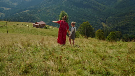 unknown woman walking daughter on green hill. mother and child enjoying vacation