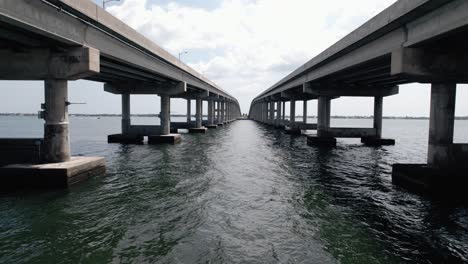 drone shot flying under bridge over water on a sunny florida day