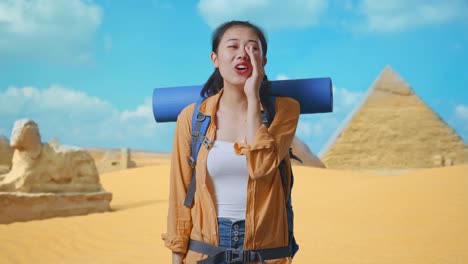 asian female hiker with mountaineering backpack screaming holding hands near her mouth while traveling in pyramid of giza